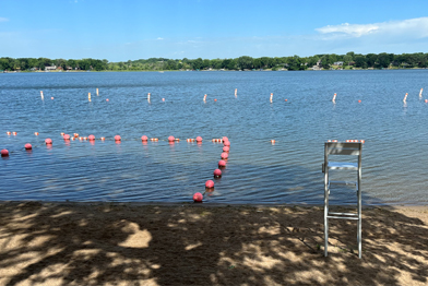 Lake with a beach and empty lifeguard chair 