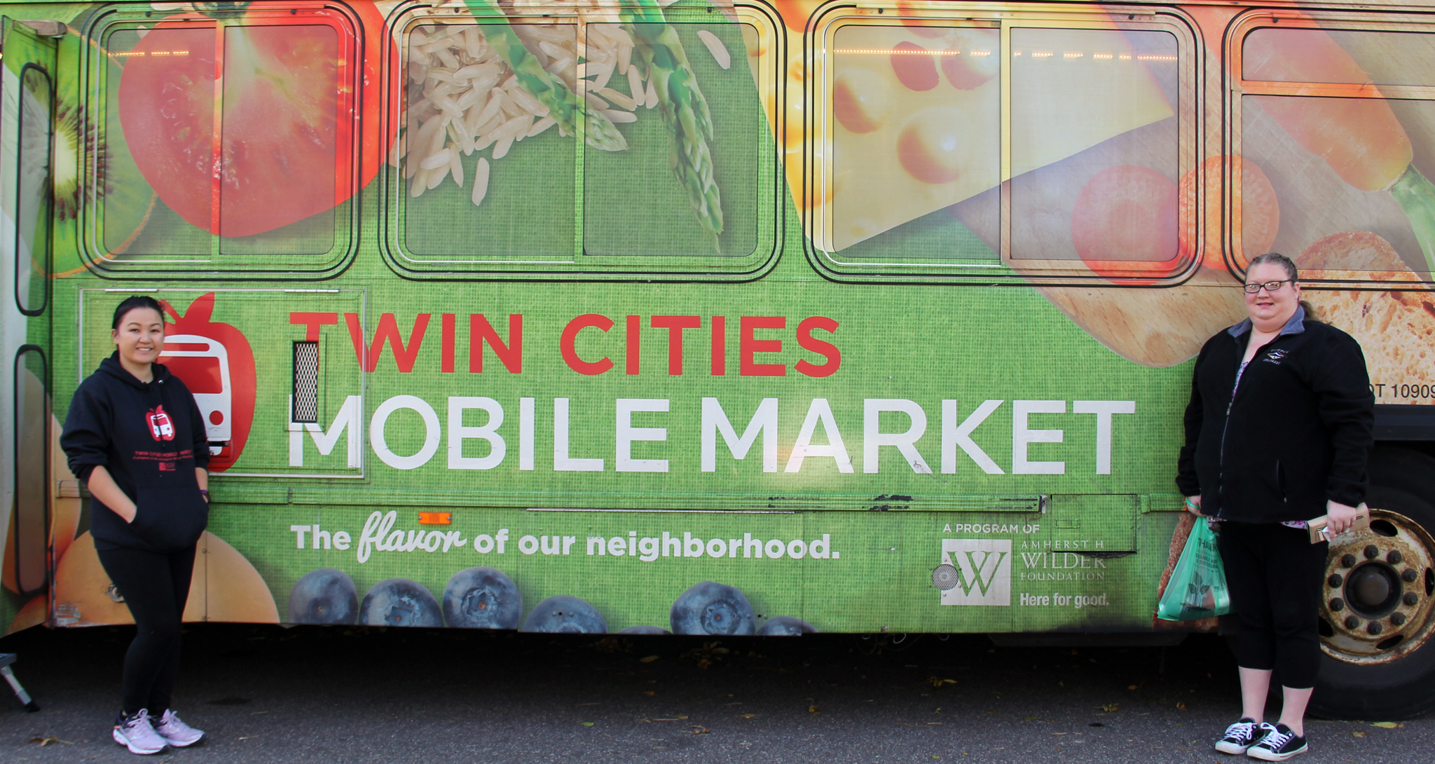 Two women standing in front of a Twin Cities Mobile Market bus