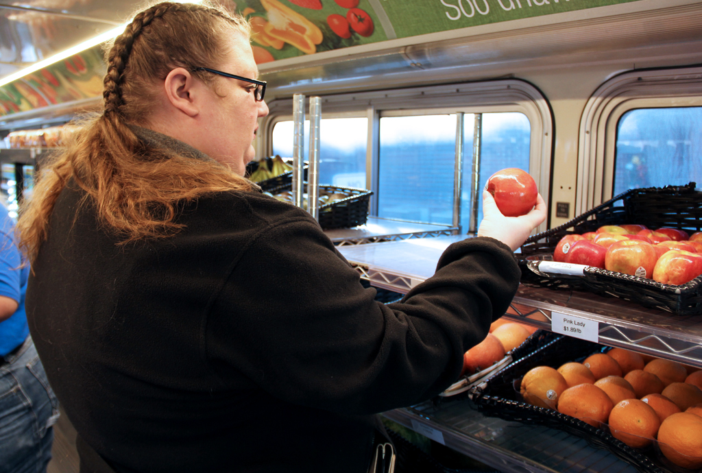 A woman examining produce on a Twin Cities Mobile Market bus