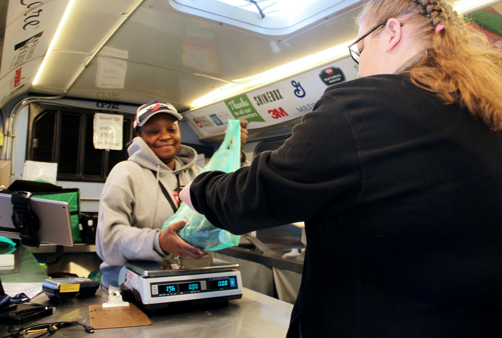 A woman purchases groceries on a Twin Cities Mobile Market bus