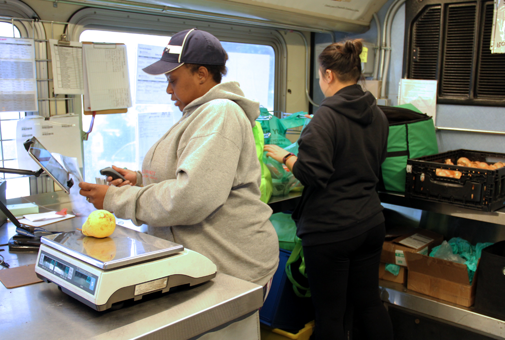 Two staff work the checkout counter on a Twin Cities Mobile Market bus
