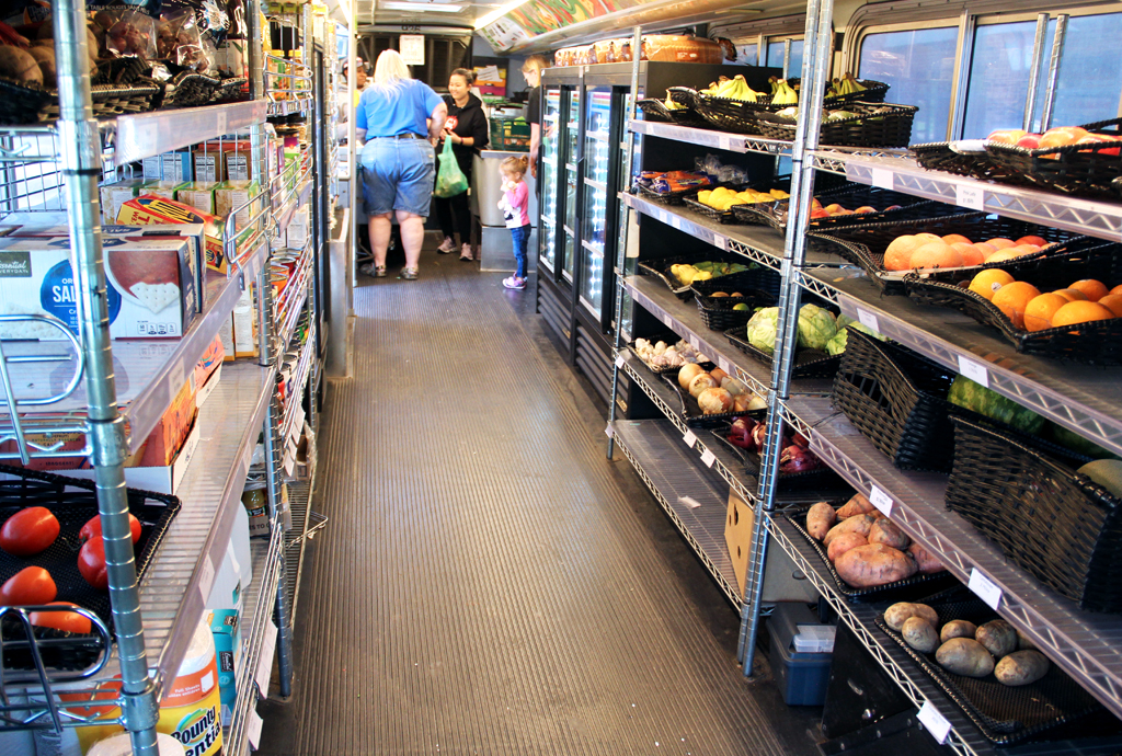 Racks of groceries and a checkout counter on a Twin Cities Mobile Market bus
