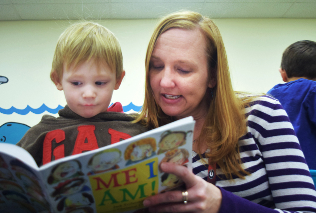 Childcare provider reads a boy a book